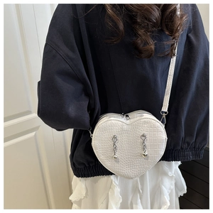 Detailed view of white heart-shaped crossbody bag with crocodile texture and silver chains