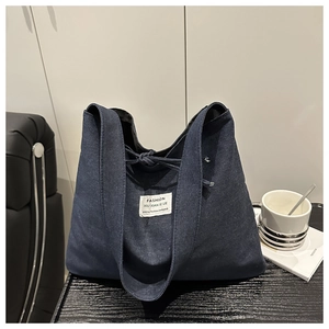 Detail of deep blue denim tote bag with fashion fabric label and drawstring closure