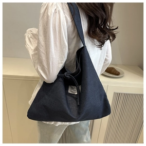 Detail of hobo style deep blue denim tote bag with knot strap and white woven label