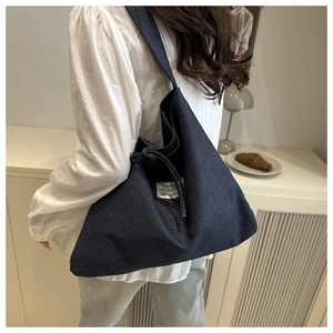 Macro detail of deep blue denim hobo bag with fashion patch and wide shoulder strap