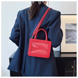 Detail of red leather crossbody bag with a transparent PVC window on a navy blazer
