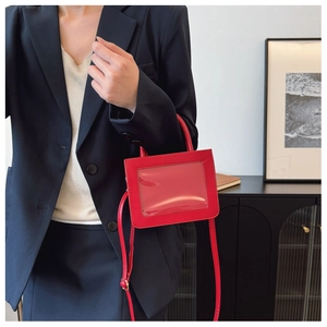 Detail of red PVC crossbody bag with transparent window and adjustable shoulder strap