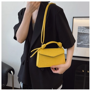 Détail d'un sac bandoulière tissé jaune avec poignée nouée et rabat de style enveloppe