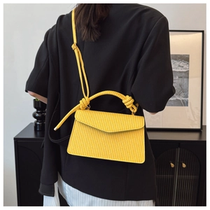 Détail du sac à bandoulière jaune tressé avec poignée nouée et sangle réglable