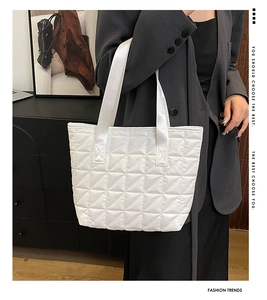 Detail view of the triangle quilted pattern and handle on a white tote bag for women