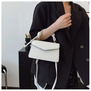 Détail d'un sac bandoulière blanc avec texture verticale et poignée en corde nouée