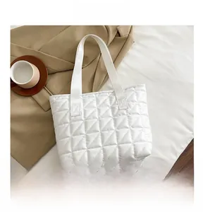 Detail showing the white quilted tote bag with rhombus pattern and soft texture