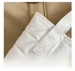 Detail shot of the reinforced stitching on the white quilted tote bag shoulder strap