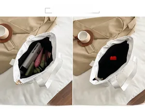Macro view of white quilted tote bag interior showing spacious main pocket and gold zipper