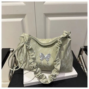 Détail du sac plissé vert clair avec papillon argenté et bandoulière nuage douce