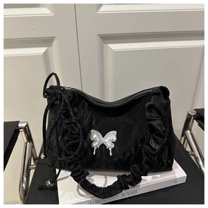 Détail du sac bandoulière noir plissé orné d'un accessoire papillon en métal argenté