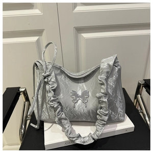 Gros plan d'un sac argenté avec bandoulière à volants et pendentif papillon chic