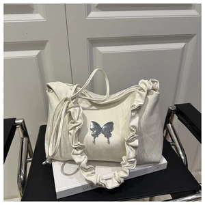 Détail du sac à bandoulière plissé crème orné d'un papillon décoratif en métal argenté