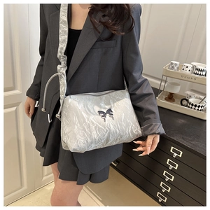 Détail d'un sac cabas argenté avec texture métal liquide et emblème papillon élégant