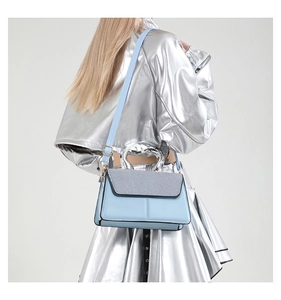 Close-up of a stylish light blue contrast small square bag with silver metal handle