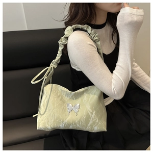 Détail du sac à bandoulière froncé jaune clair avec papillon en métal et anse plissée