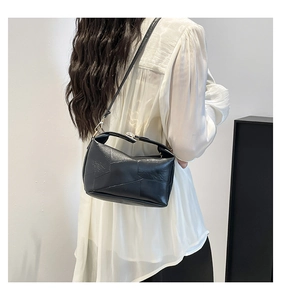 Detail of a minimalist black geometric patchwork shoulder bag on a female model