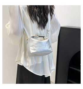 Detail of silver pleated crossbody bag with gold hardware and metallic texture