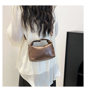 Detail of a brown leather patchwork handbag with a sleek crossbody strap on model