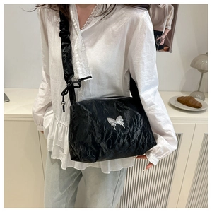 Détail du sac à bandoulière noir texture froissée avec boucle papillon métallique argentée
