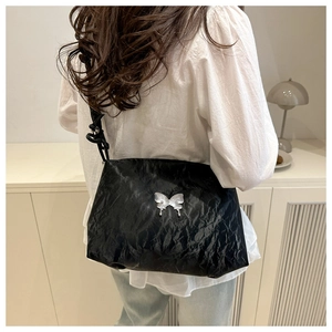 Détail du sac cabas plissé noir avec papillon en métal argenté et bandoulière nouée