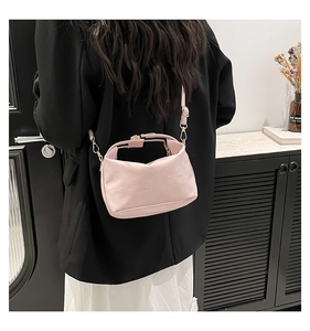 Light pink woven shoulder bag with golden metallic lock shown on a model