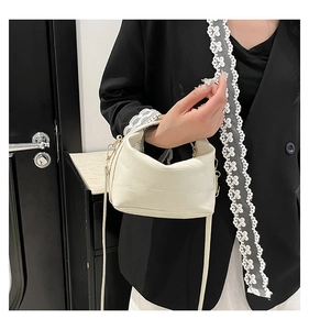 Detail of cream white leather handbag featuring geometric paneling and gold hardware