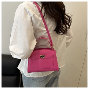 Detail of rose pink lychee leather crossbody bag on a model wearing white shirt