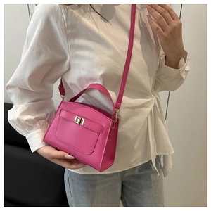 Detail view of fuchsia litchi grain leather bag with golden metal turn-lock closure