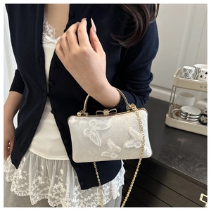 Detailed embroidery with 3D butterfly appliqués on white lace clutch with gold handle