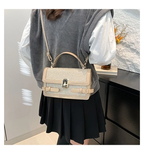 Detailed view of beige glitter crossbody bag with metallic turn-lock and leather handle