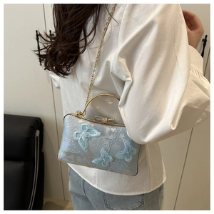 Detail of light blue embroidered butterfly handbag with sparkling golden bow closure