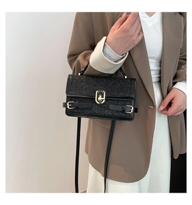 Detail of black sequined crossbody bag with gold hardware and stylish turn-lock closure