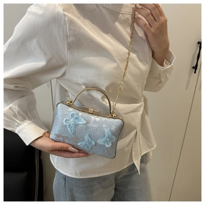 Detail of light blue crossbody bag with 3D butterfly embroidery and gold metal handle