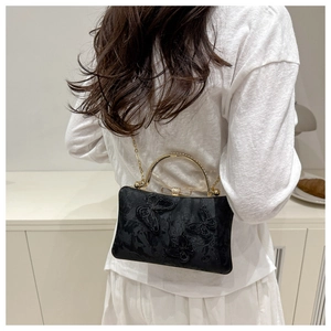 Detail of black evening clutch featuring 3D butterfly embroidery and gold chain strap