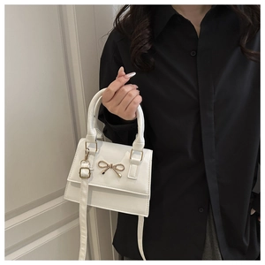 Detailed shot of white tote bag with golden metal bow buckle and elegant handle