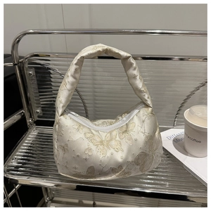 Detail of ivory jacquard shoulder bag with golden butterfly pattern and top handle