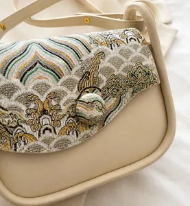 Close-up of cream leather bag featuring intricate jacquard landscape embroidery details
