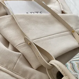 Close-up of beige twill canvas bag with leather strap detail and high-quality stitching