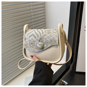 Close-up of vintage beige crossbody bag with intricate Chinese wave embroidery details