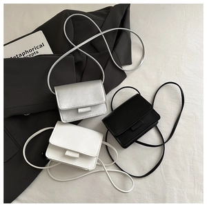 Flat lay of minimalist mini flap crossbody bags in silver, black and white finishes