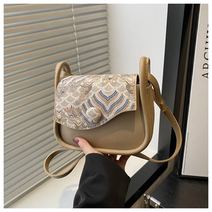 Detailed macro view of vintage crossbody bag featuring ethnic floral embroidery and leather texture