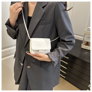 Close-up of a white mini PU leather crossbody bag worn with a gray modern suit