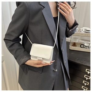 Detailed view of a white mini square crossbody bag on a model with a clean flap design