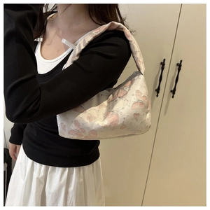 Détail du sac à bandoulière crème avec tissu jacquard à papillons roses et fermeture éclair