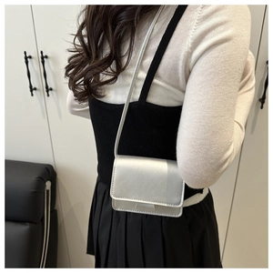 Silver square crossbody bag with metallic finish and slim shoulder strap on model