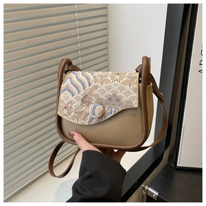 Detail of vintage crossbody bag with traditional embroidery and brown leather trim