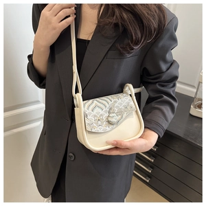 Detail of cream saddle bag with vintage oriental embroidery and elegant leather texture