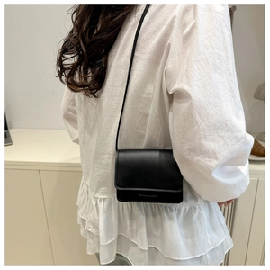 Minimalist black leather square shoulder bag shown on model for a trendy casual look