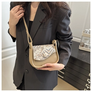 Detailed shot of a beige jacquard saddle bag featuring intricate wavy embroidery on flap